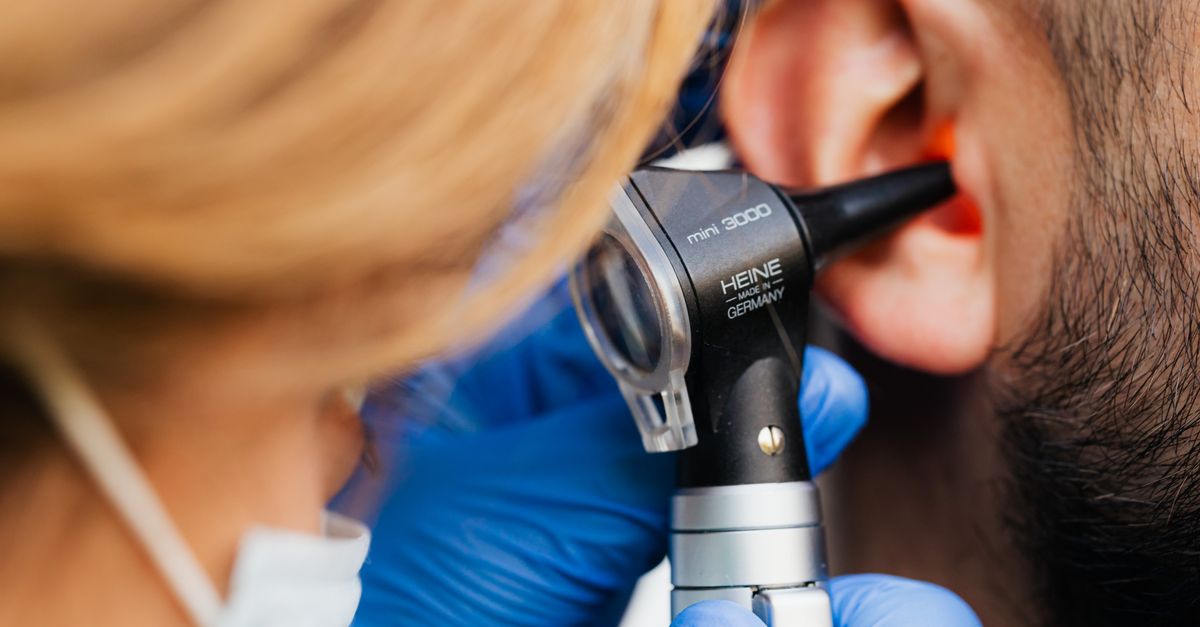 A medical professional examines a patient's ear using a Heine otoscope, highlighting healthcare quality.